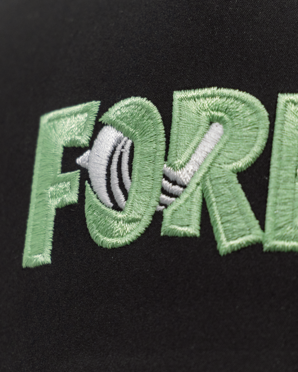 Close-up of a black cap featuring green embroidered text reading &